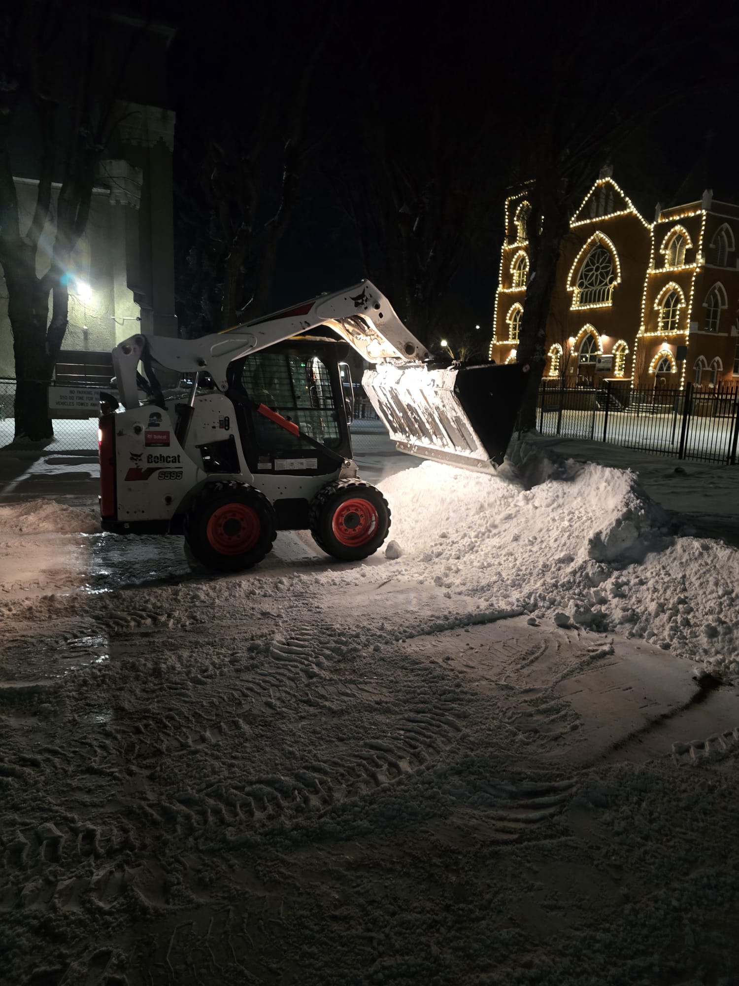 Bobcat skid steer pushing snow across a commercial parking lot in Edmonton