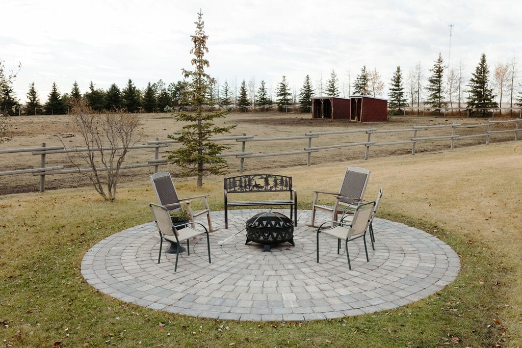 Circular paver fire pit patio with seating on an acreage